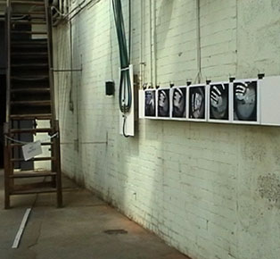 photo of speaker in situ next to wooden stairs and B & W photographs exhibited by Marcus Gaudoin